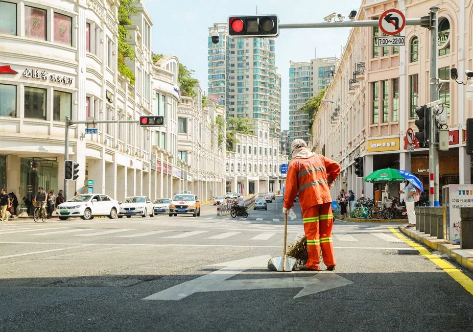 A person in protective gear sanitizing an office desk using fumigation equipment during daytime.